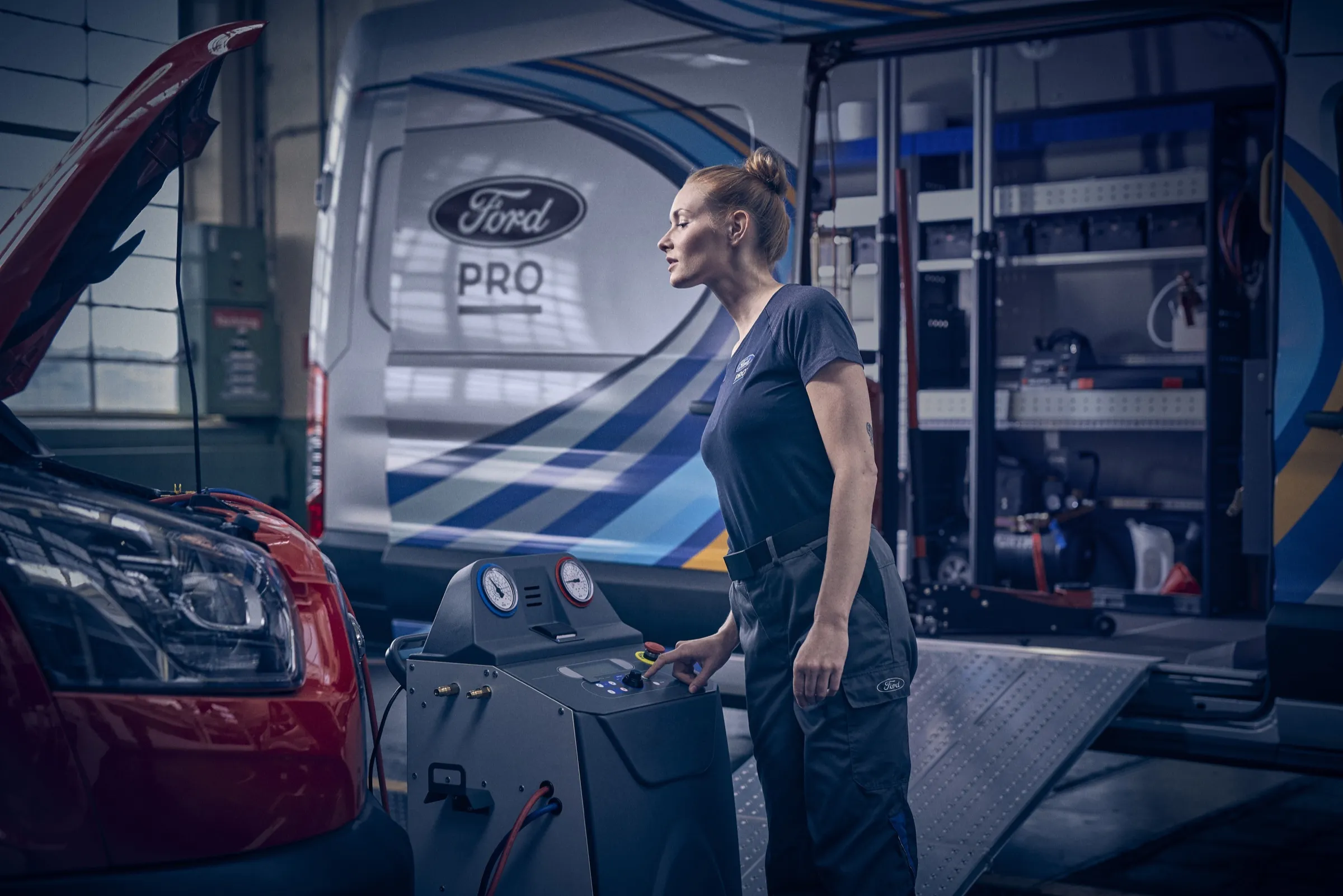 Servicetechnikerin am Klimaservicegerät neben einem Fahrzeug mit geöffneter Motorhaube