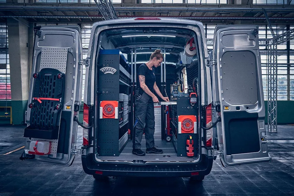 Servicetechnikerin im voll ausgestatteten Laderaum eines Ford-Pro-Service-Vans mit Regalsystem
